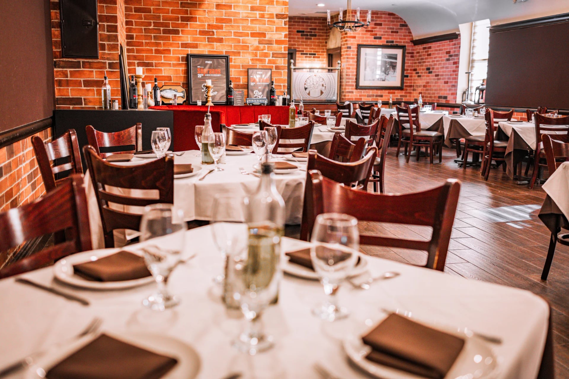 White-clothed dining tables set with wine glasses in the Da Nico Ristorante dining room on Mulberry Street, Little Italy