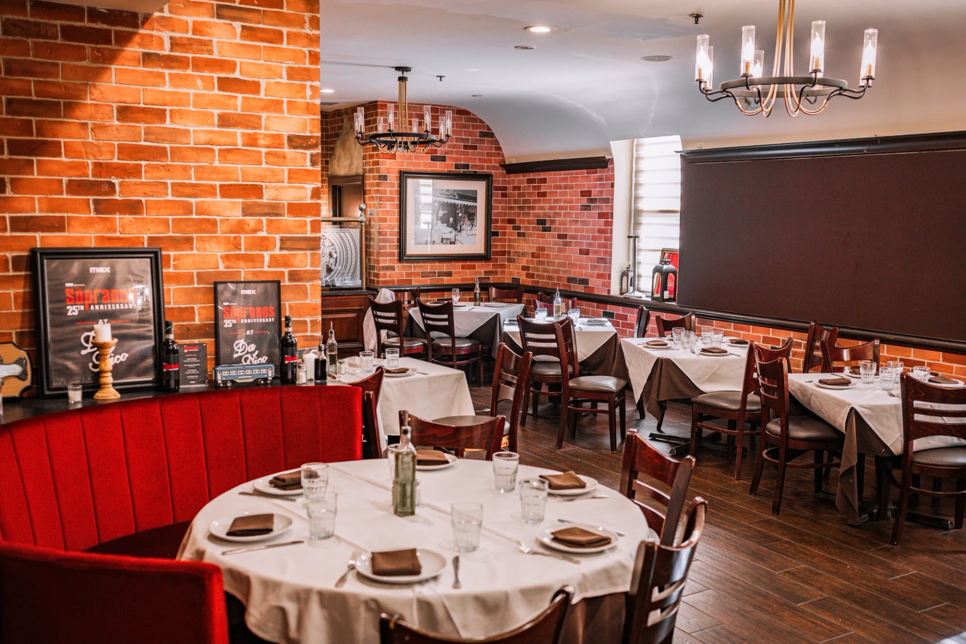 Long dining room at Da Nico Ristorante with rows of white-clothed tables and framed mirrors on Mulberry Street
