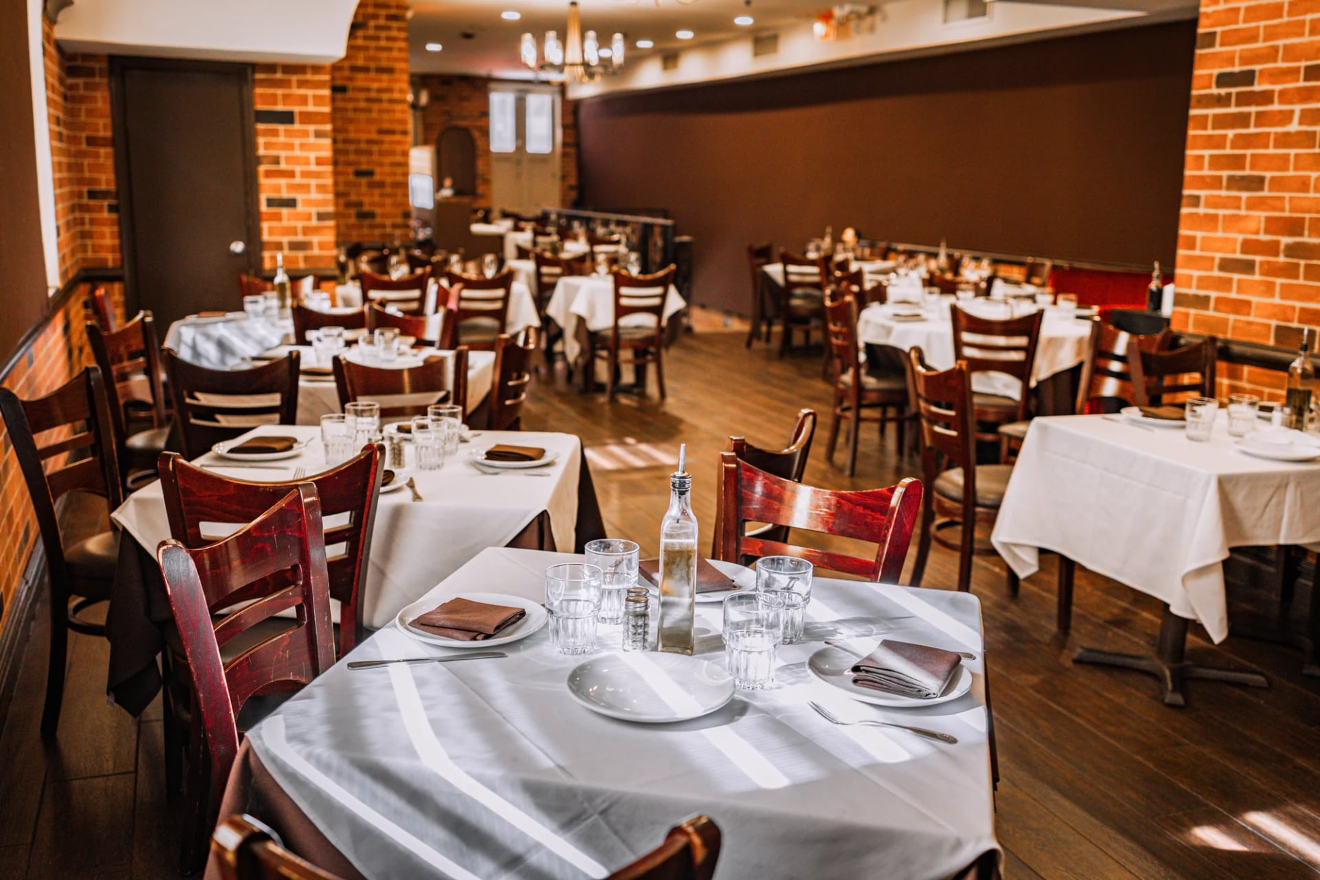 White-clothed tables and black chairs along the mirrored wall of the Da Nico dining room in Little Italy