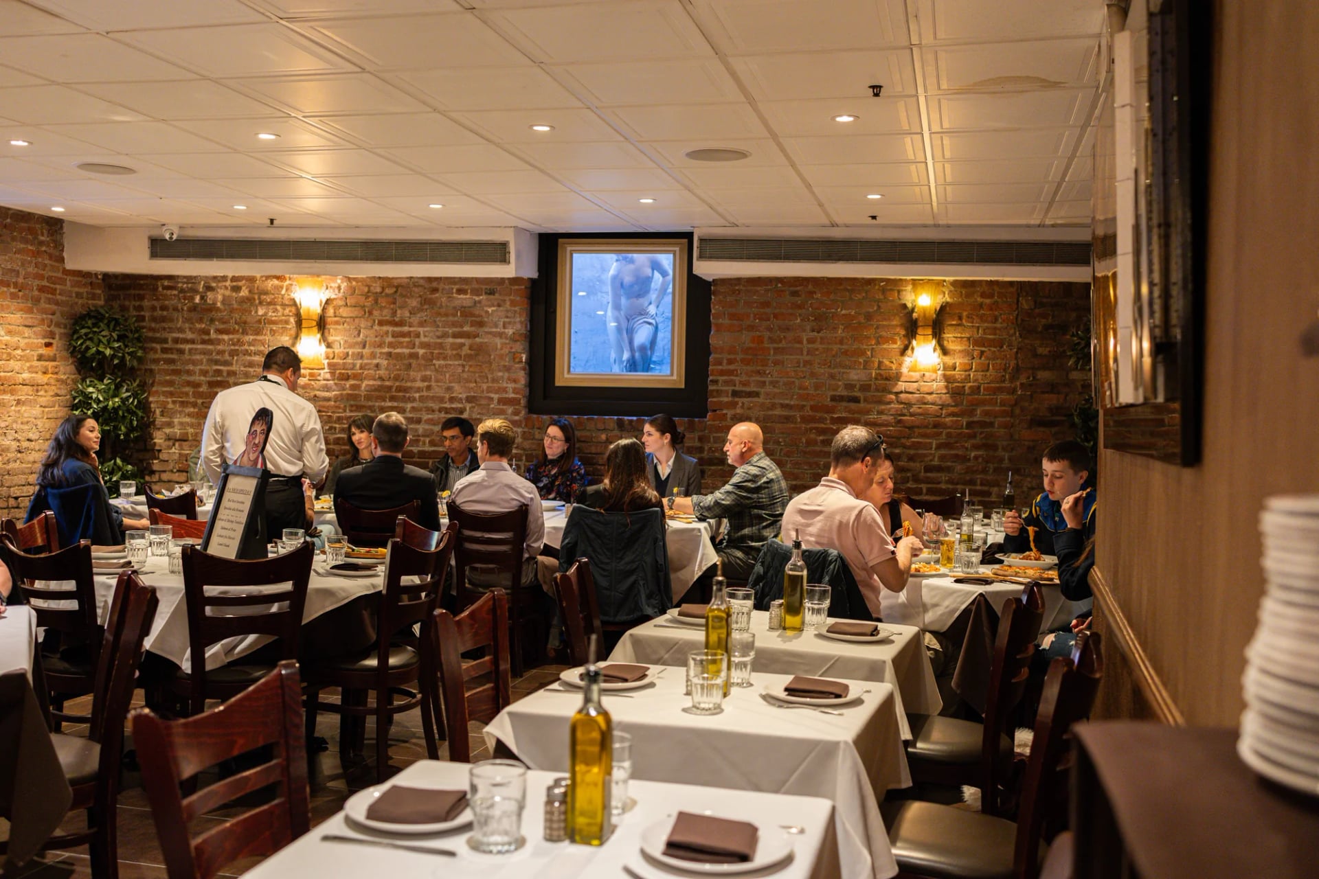 Diners at round tables under chandeliers in the Da Nico Ristorante dining room