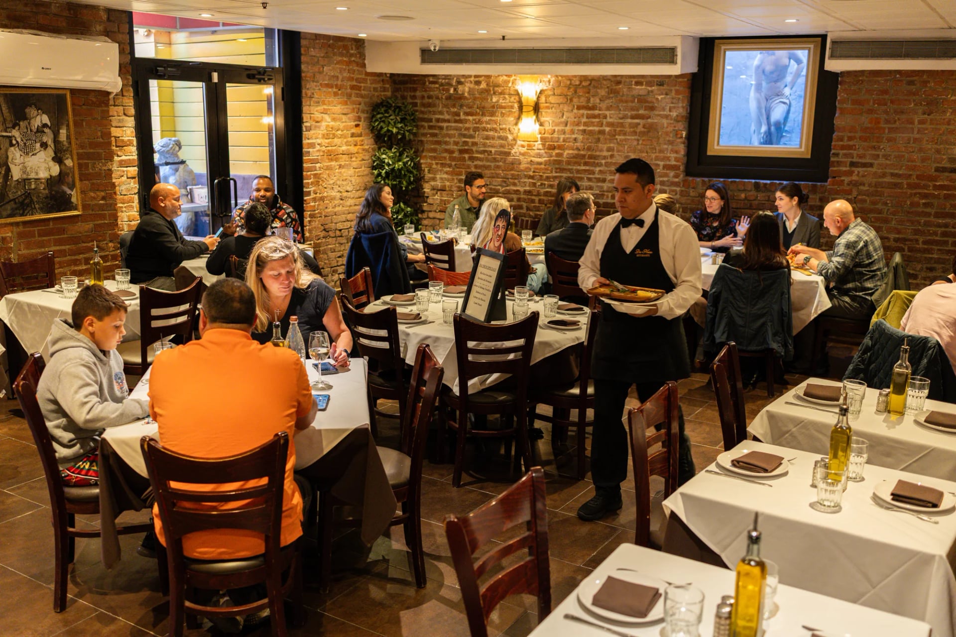 Guests dining beside the exposed brick wall at Da Nico Ristorante in Little Italy